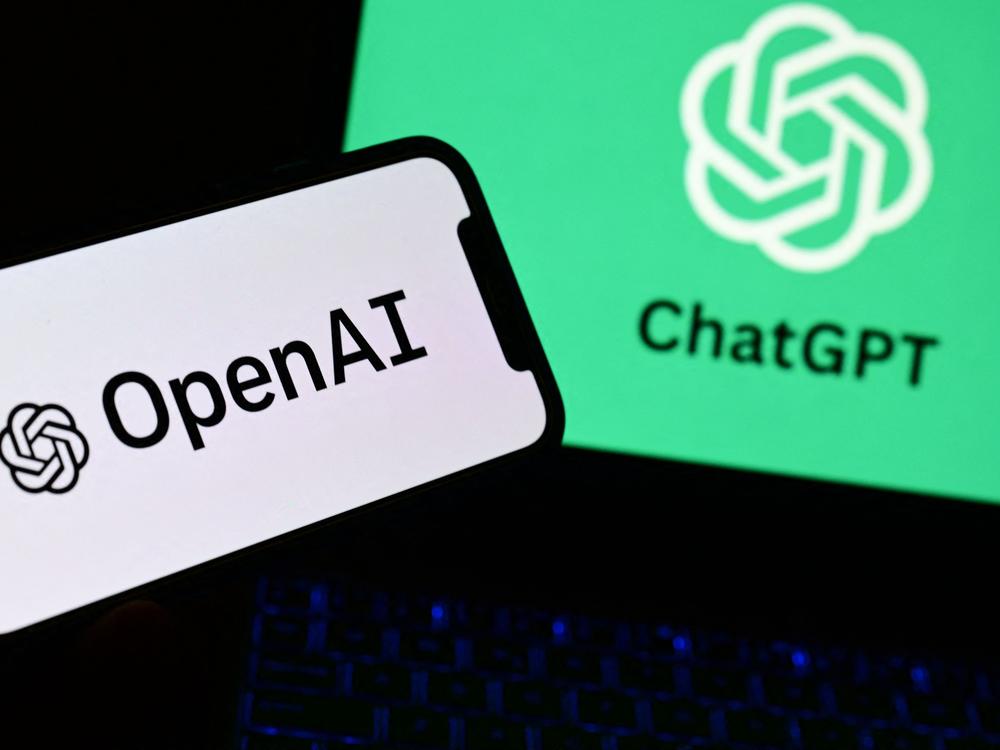 A photo taken on October 4, 2023 in Manta, near Turin,  shows a smartphone and a laptop displaying the logos of the artificial intelligence OpenAI research laboratory and ChatGPT robot.