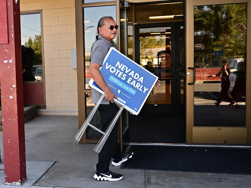 Little Buck Harjo carries 'Nevada Votes Early' signs at the reno-Sparks Indian Colony in Reno, Nev., on Oct. 15, 2024.