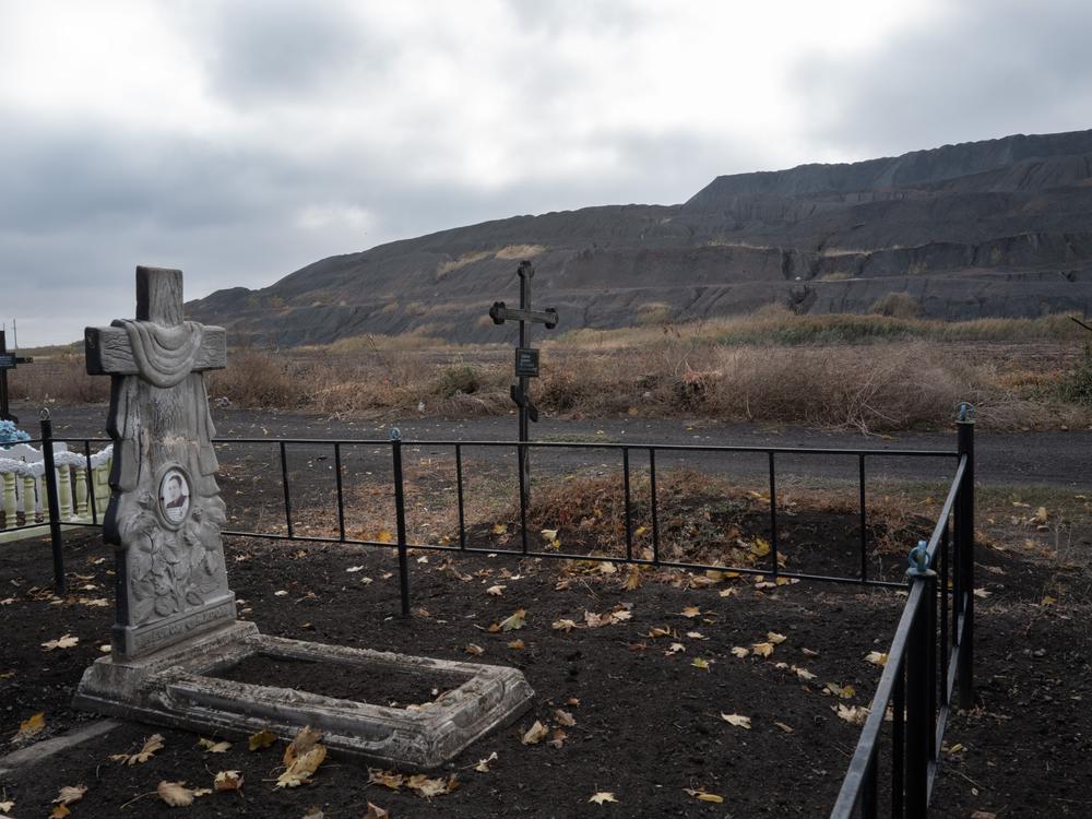 A slag heap from a nearby coal mine is seen from a cemetery at the edge of the mining town of Dobropillya, Ukraine, on Oct. 17.