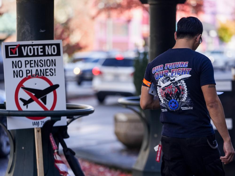 A Boeing employee walks by a picket sign urging people to vote no on a new contract offer from the company on Monday in Everett, Wash.