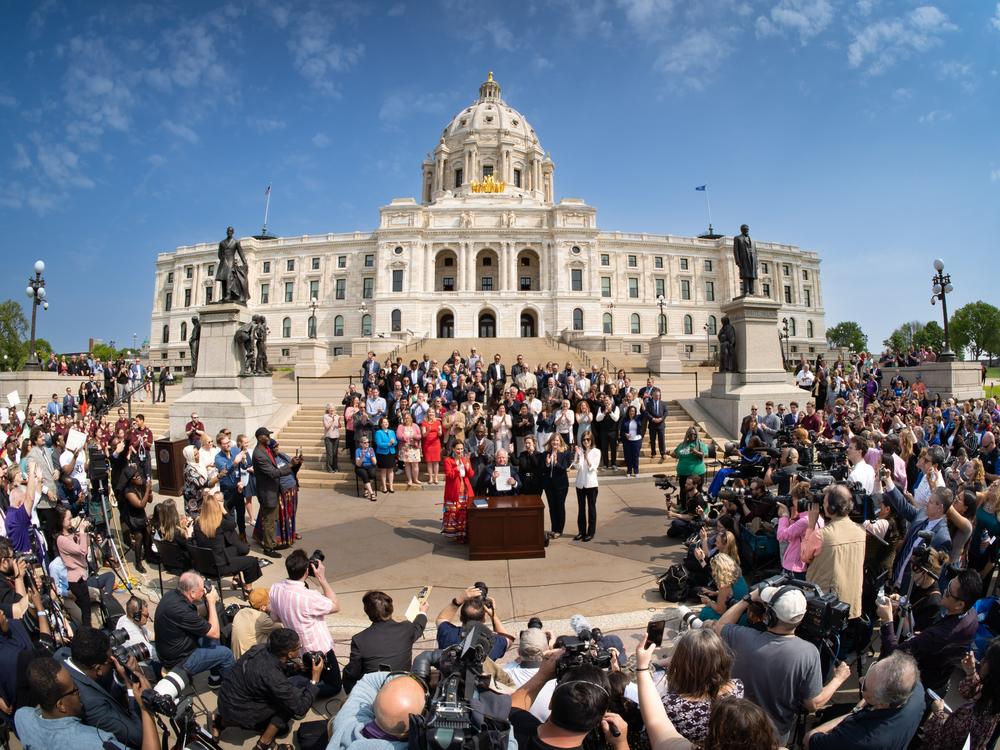 Minnesota Gov. Tim Walz signs the budget bill on May 24, 2023, on the steps of the State Capitol in St. Paul, Minn., in front of hundreds of supporters.