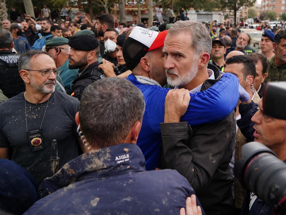 King Felipe VI of Spain is hugged by a man as other angry residents heckled him during his visit to Paiporta, in the region of Valencia, eastern Spain, on November 3, 2024, in the aftermath of devastating deadly floods.