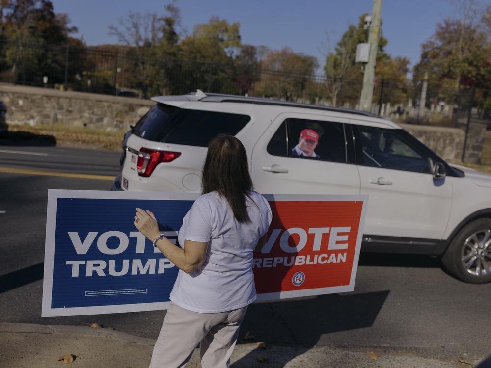 A Republican supporter holds a sign backing presidential candidate Donald Trump for drivers passing by the Staten Island Republican Party headquarters.