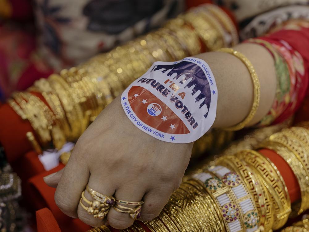 Ripa Ahmed, 50, a local business owner in Jackson Heights, displays her voter sticker as she tends to clients inside her store.