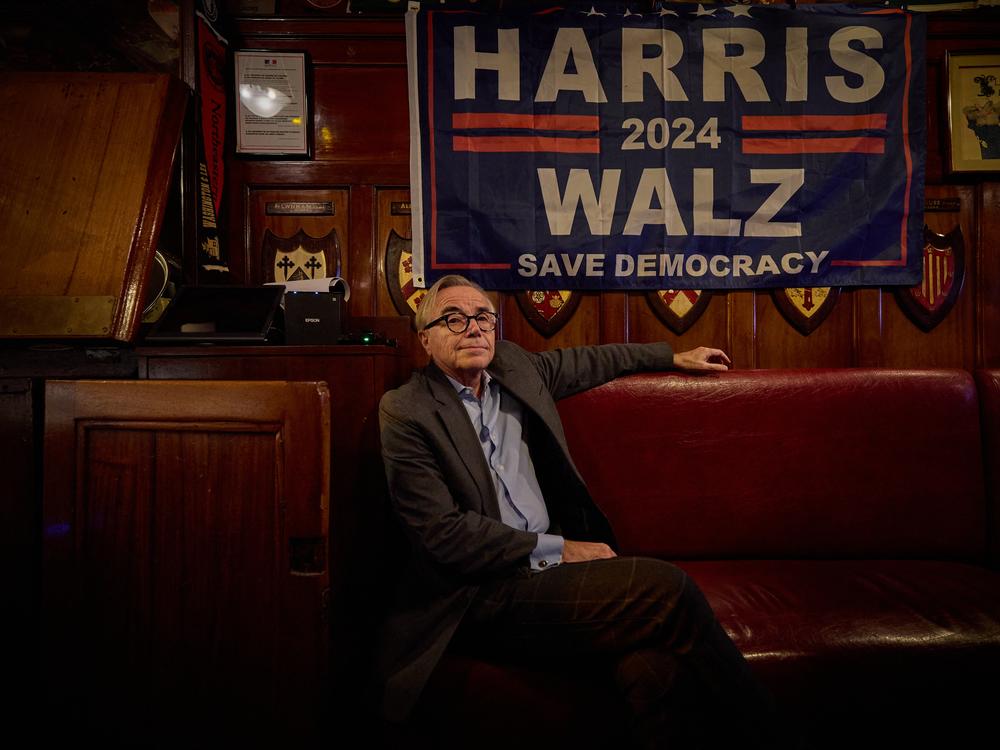 A man sits beneath a Kamala Harris-Walz election sign as he watches coverage of the U.S. presidential election at Harry's Bar in Paris on Tuesday.