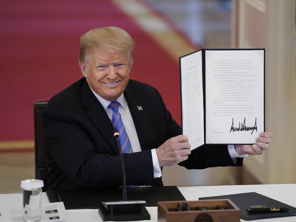 Then-President Donald Trump signs an executive order related to reforming the hiring process for federal jobs on June 26, 2020.
