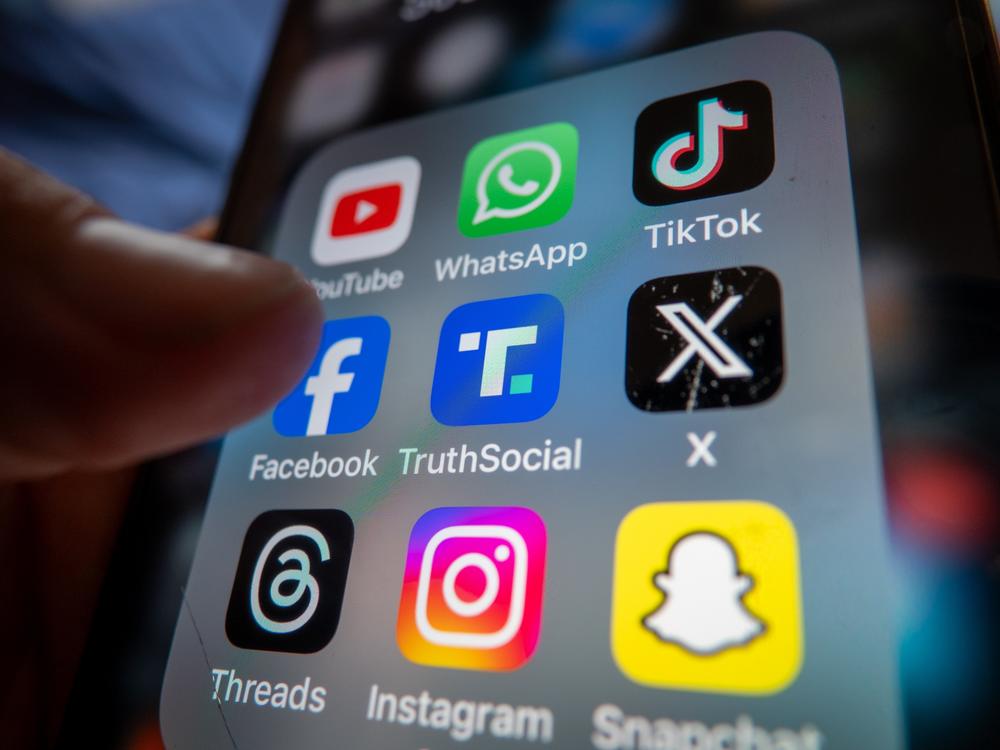 A smartphone screen displays the logo of various social media platforms.