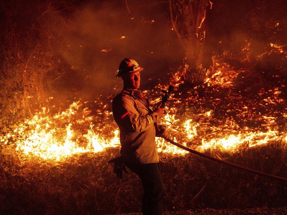 A firefighter prepares to douse flames while battling the Mountain Fire on Wednesday, Nov. 6, 2024, in Santa Paula, Calif.
