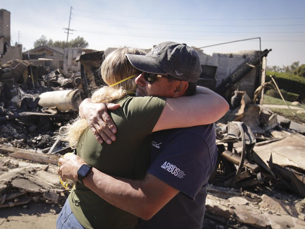Kelly Barton, left, is hugged by a family friend after arriving at her parents' fire-ravaged property in the aftermath of the Mountain Fire, Thursday, Nov. 7, 2024, in Camarillo, Calif.
