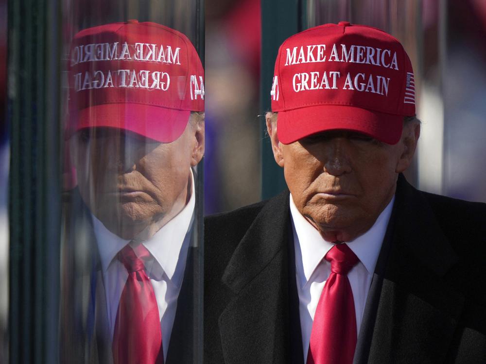 Former President Donald Trump is reflected in the bullet proof glass as he finishes speaking at a campaign rally in Lititz, Pa., on Nov. 3.