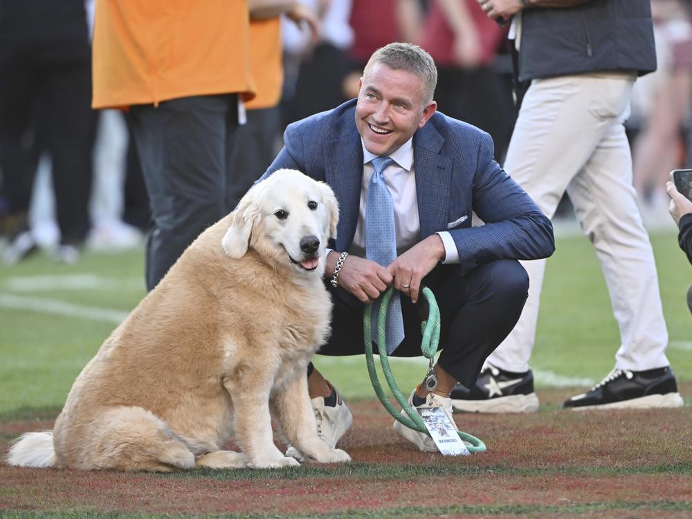 ESPN's Kirk Herbstreit and his dog Ben watch players warm up before the start of an NCAA college football game between Tennessee and Arkansas on Oct. 5 in Fayetteville, Ark.