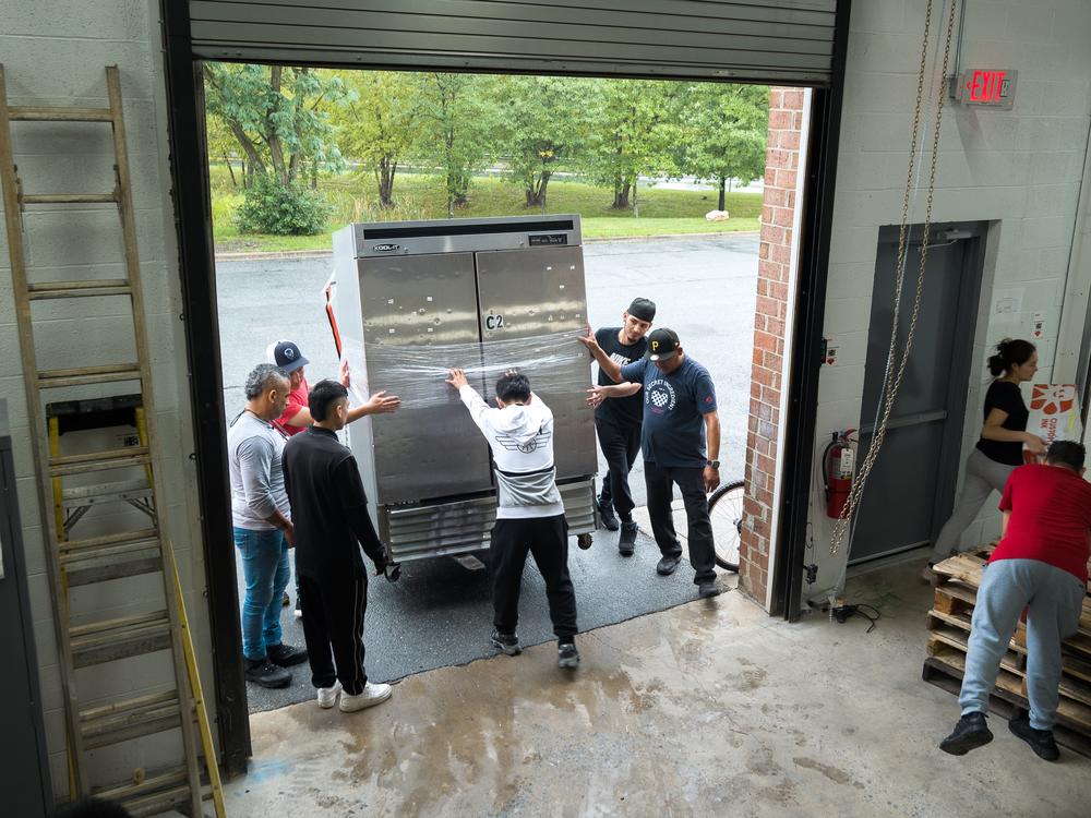 Employees move a refrigerator during MasPanadas move to their new facility in Rockville MD.