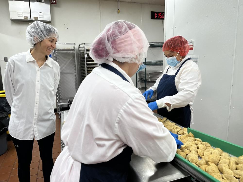 Margarita Womack, owner of the frozen empanadas company MasPanadas, (left,) looks over staffers inspecting empanadas to ensure quality control. Imperfect empanadas such as those with an uneven shape are removed and donated.