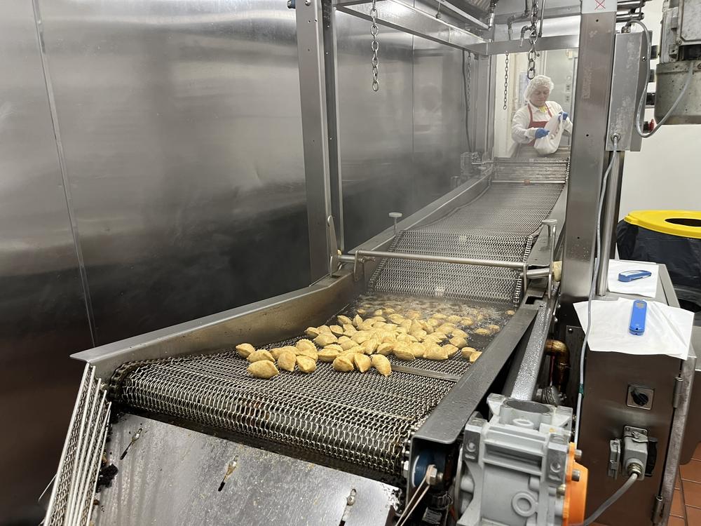 A worker at MasPanadas feeds pastries or turnovers into the fryer. The machine was brought in from Colombia and once the empanadas roll out, they are inspected for any imperfection.
