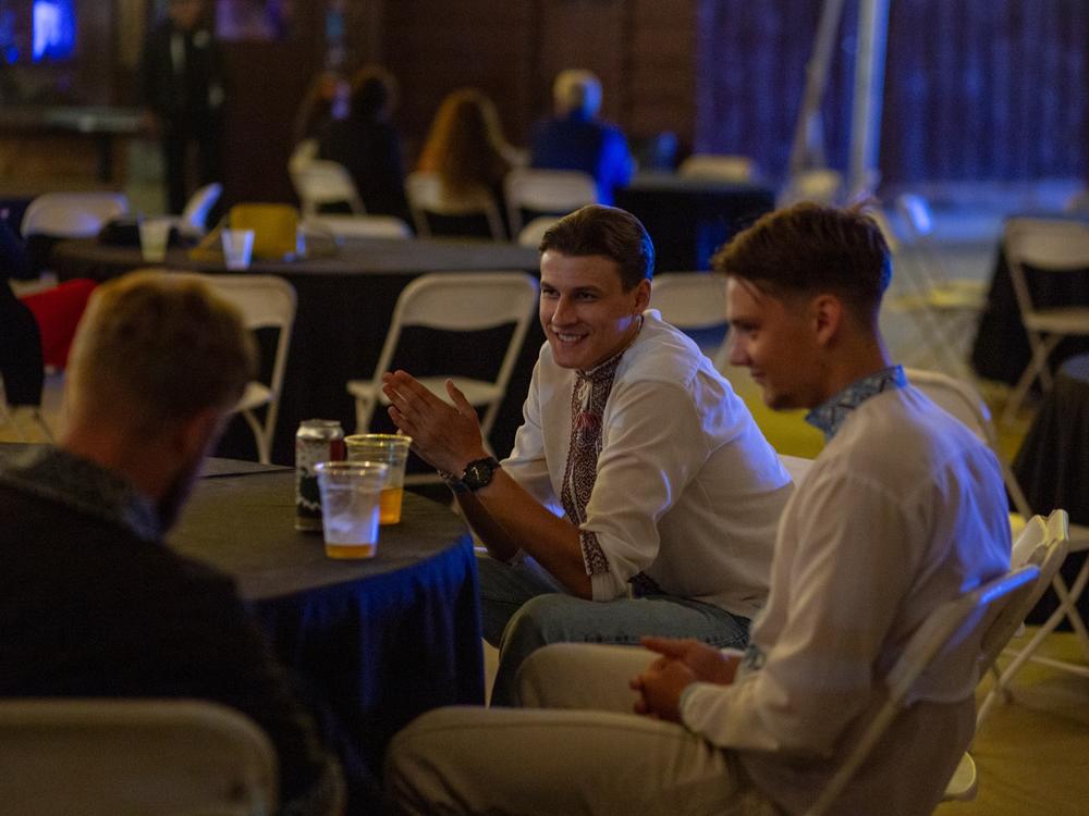 A group of young men in embroidered shirts enjoy a drink while waiting for the dance floor to fill up.