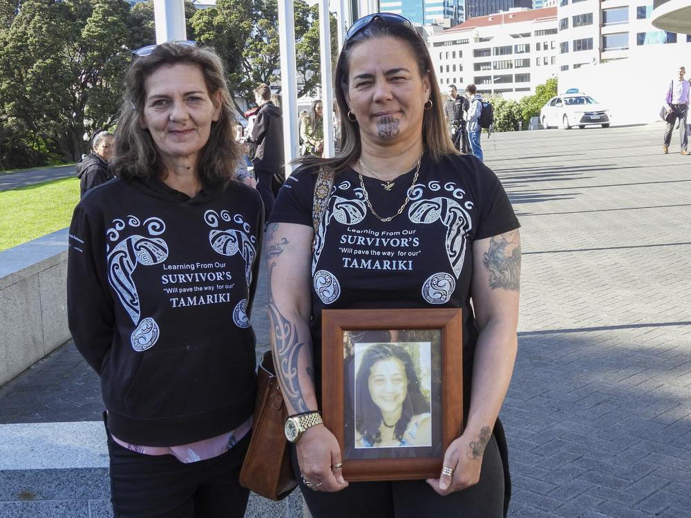 Gina, right, and Tanya Sammons hold a photo of their late sister Alva as they arrive at Parliament House in Wellington, New Zealand, ahead of the apology to the survivors of abuse in state, faith-based and foster care over a period of seven decades.