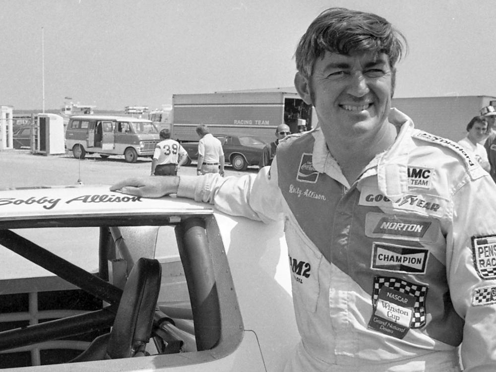 Bobby Allison stands beside his car and talks with the press after winning the pole position during qualifying for the 500 mile grand national stock car race at Pocono Raceway, Aug. 2, 1975, in Long Pond, Pa.