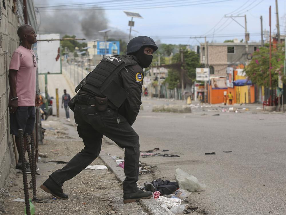 A police officer looks on during an exchange of gunfire between gangs and police in Port-au-Prince, Haiti on Monday.
