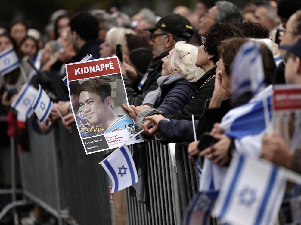 At an Oct. 6 gathering in Paris in tribute to victims of the Hamas-led Oct. 7, 2023, attack on Israel, a woman holds a portrait of Thai hostage Pongsak Thaenna, kidnapped by Hamas and held in the Gaza Strip.