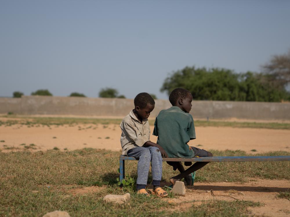 Mahawat Zakaria Jouma's younger brothers, Hassan and Hussein, sit together on a bench at the soccer field where their brother likes to play.