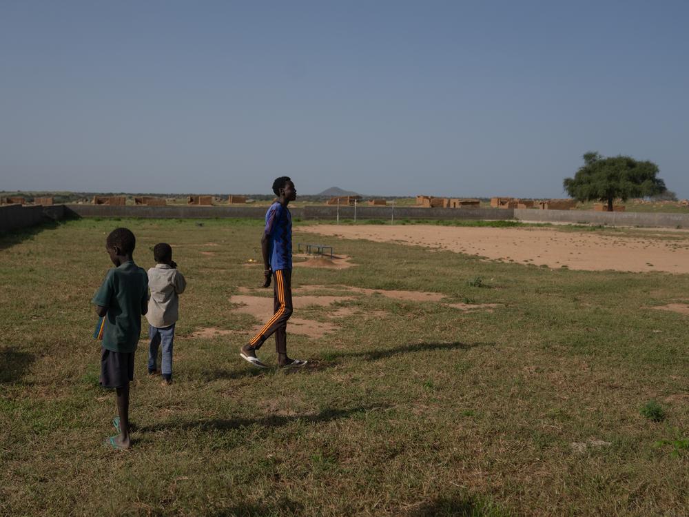 Mahamat DJouma, 14, with two of his younger brothers at the soccer field where he likes to play. He has nicknames for the boys: 