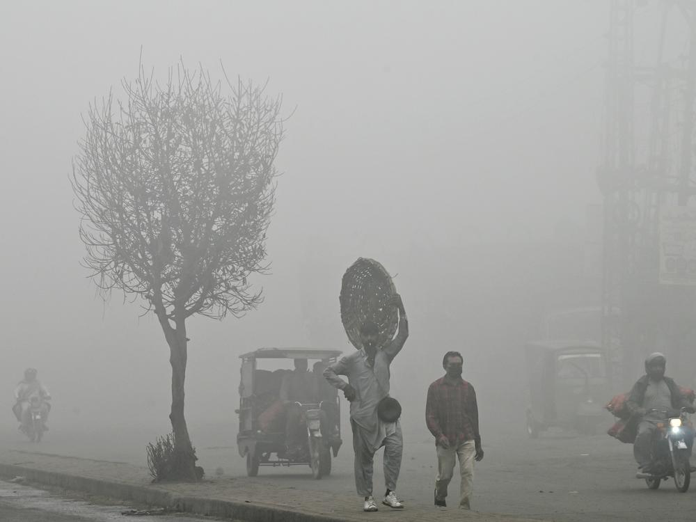 Pedestrians walk along a road engulfed in thick smog in Lahore, Pakistan, on Nov. 11. Lahore, a city of 14 million people and stuffed with factories, regularly ranks among the world's most polluted cities. It's hit record levels this month.