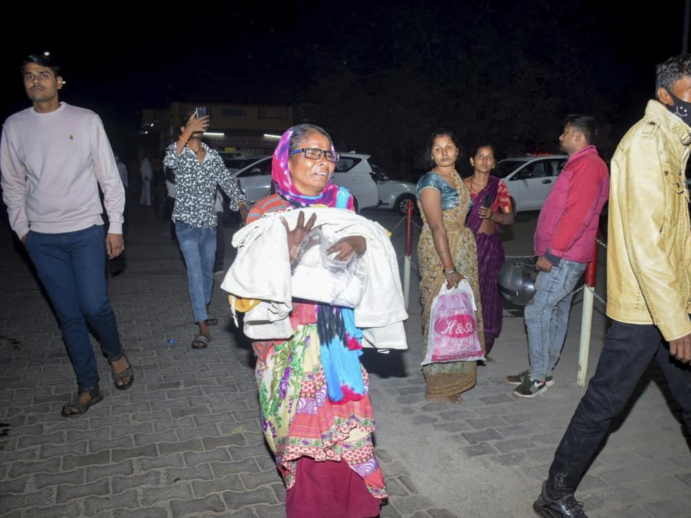 A woman rushes a child to the emergency ward after a fire broke out in a neonatal intensive care unit at Jhansi Medical College hospital in Jhansi, India, on Friday.