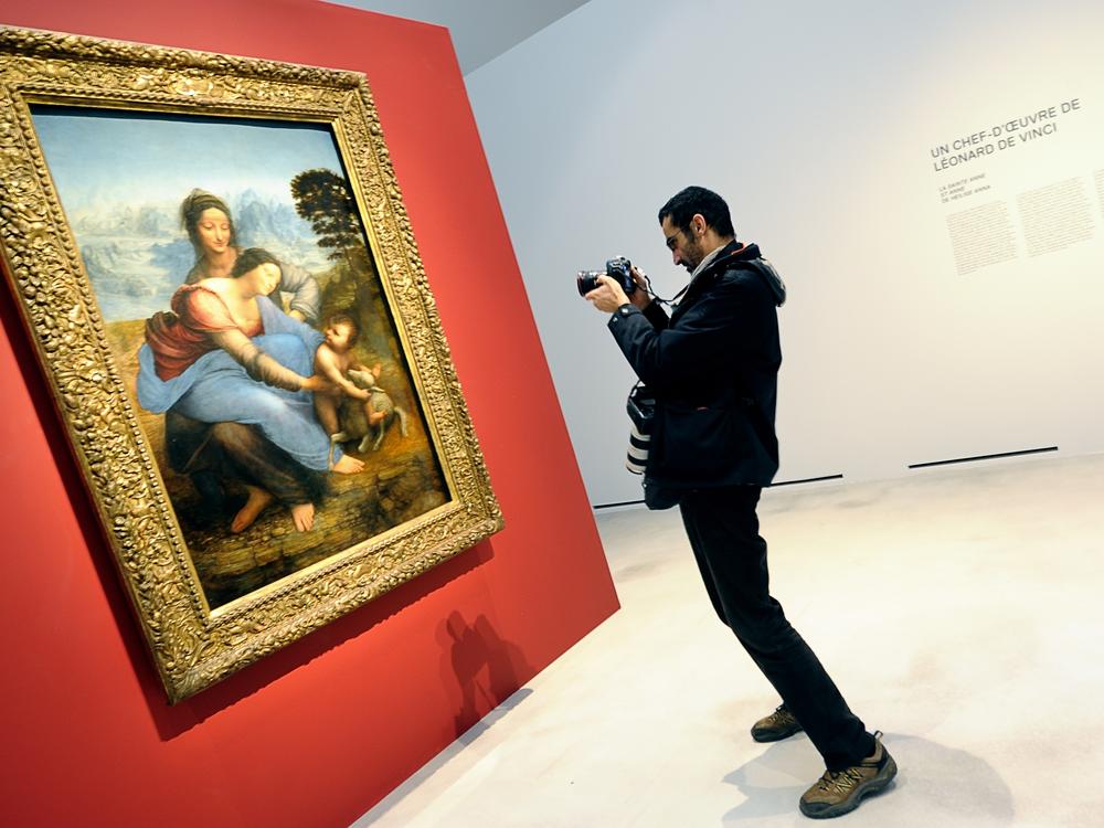 A visitor takes a picture of The Virgin and Child with Saint Anne in the Louvre in 2012.