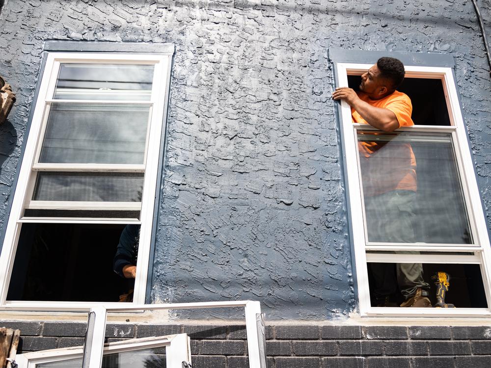 A worker with Lyon Contracting Services installs new windows at a home in Kensington, a Philadelphia neighborhood heavily impacted by the drug overdose epidemic. Free repairs at 400 homes in Kensington were paid for by settlement funds from opioid-related lawsuits. A Pennsylvania oversight board ruled that the repairs did not comply with guidelines on how the money should be spent.