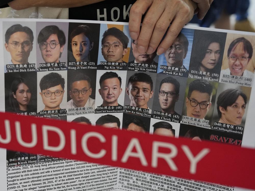 A supporter holds a placard with the photos of some of the 47 pro-democracy defendants outside a court in Hong Kong, on July 8, 2021.