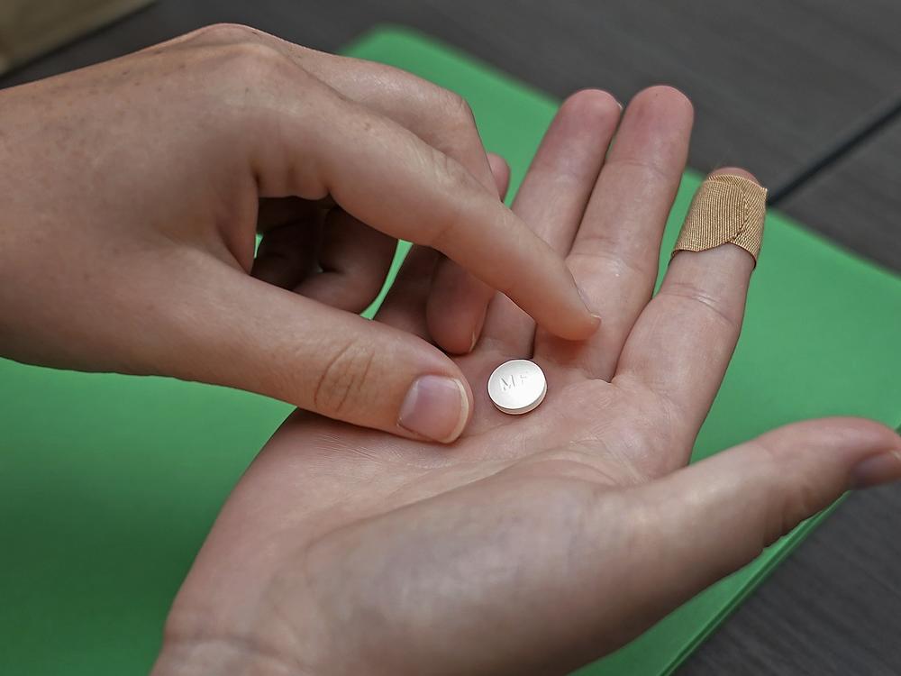 A patient prepares to take the first of two combination pills, mifepristone, for a medication abortion during a visit to a clinic in Kansas City, Kan. in 2022.