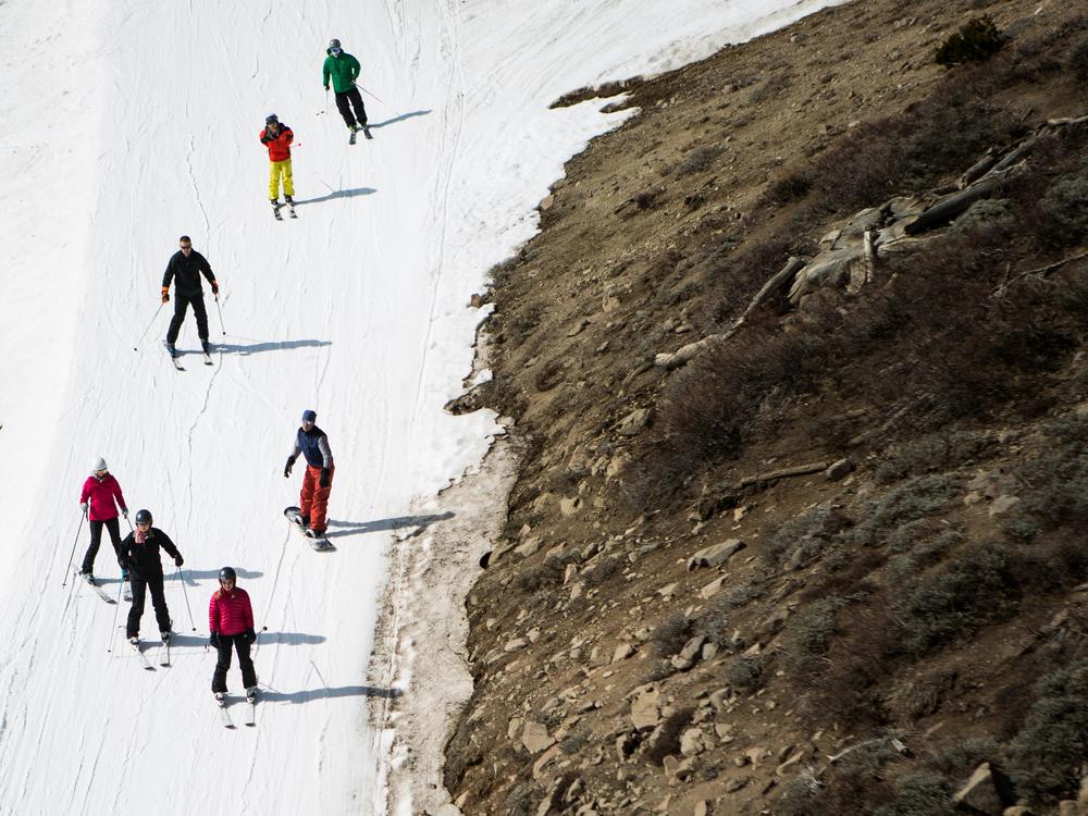 Skiers ski past dry ground at a ski resort in 2015 in Olympic Valley, Calif. The resort changed its name in 2021 and has been among the places removing a derogatory word from their names.
