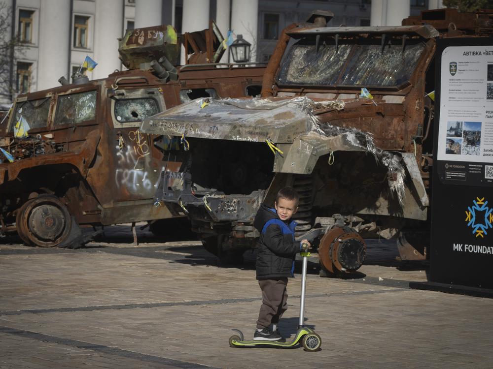 A boy rides a scooter past a display of destroyed Russian military vehicles in Mykhailivska square in central Kyiv, Ukraine on Tuesday, Oct. 22, 2024.