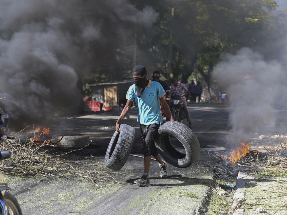 A resident carries tires to be added to a burning barricade to deter gang members from entering his neighborhood, in Port-au-Prince, Haiti on Tuesday.