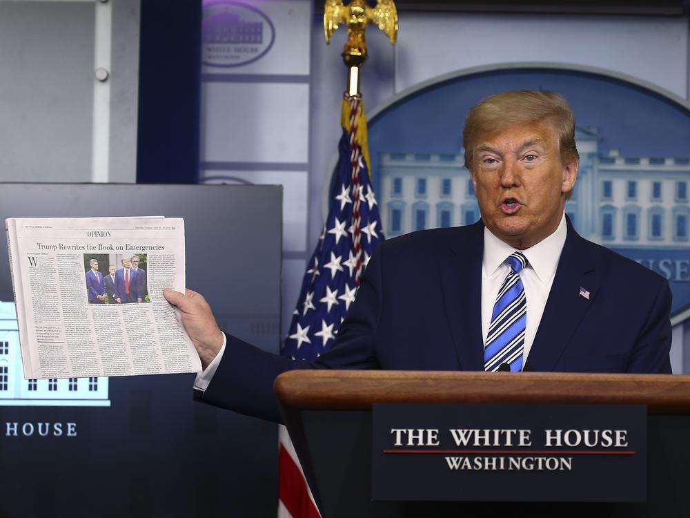 Then-President Donald Trump holds up <em>The Wall Street Journal </em>as he speaks at the White House on April 19, 2020.