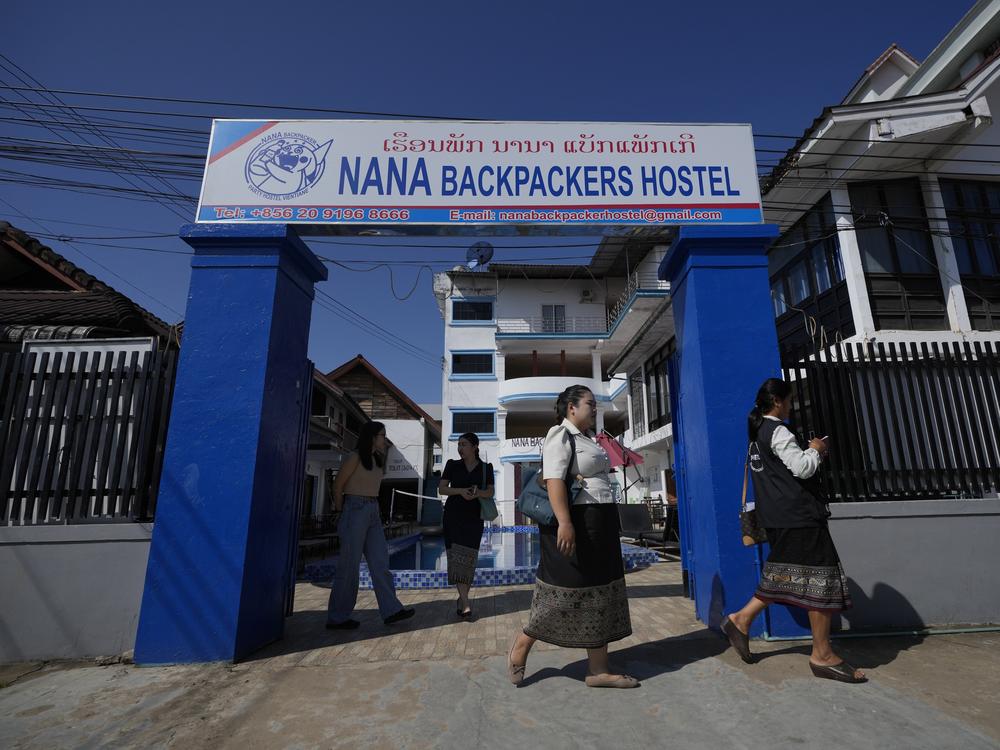 Health officials come out of Nana Backpackers Hostel after checking documents in Vang Vieng, Laos, on Friday.