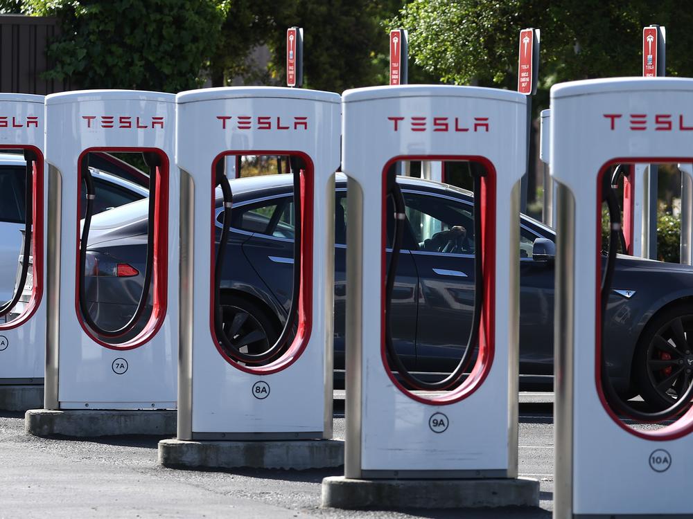 A Tesla charges at a Tesla Supercharger in Petaluma, Calif., in May. Tesla's Supercharger network has more than 30,000 fast-charging ports — more than half of all the EV fast chargers available in the United States. Until recently, they were only open to Tesla drivers, but that's changing.