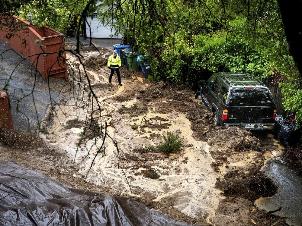 Permit Sonoma Director Tennis Wick crosses a mudslide to inspect a home as heavy rains fall near Healdsburg in unincorporated Sonoma County, Calif., on Friday.