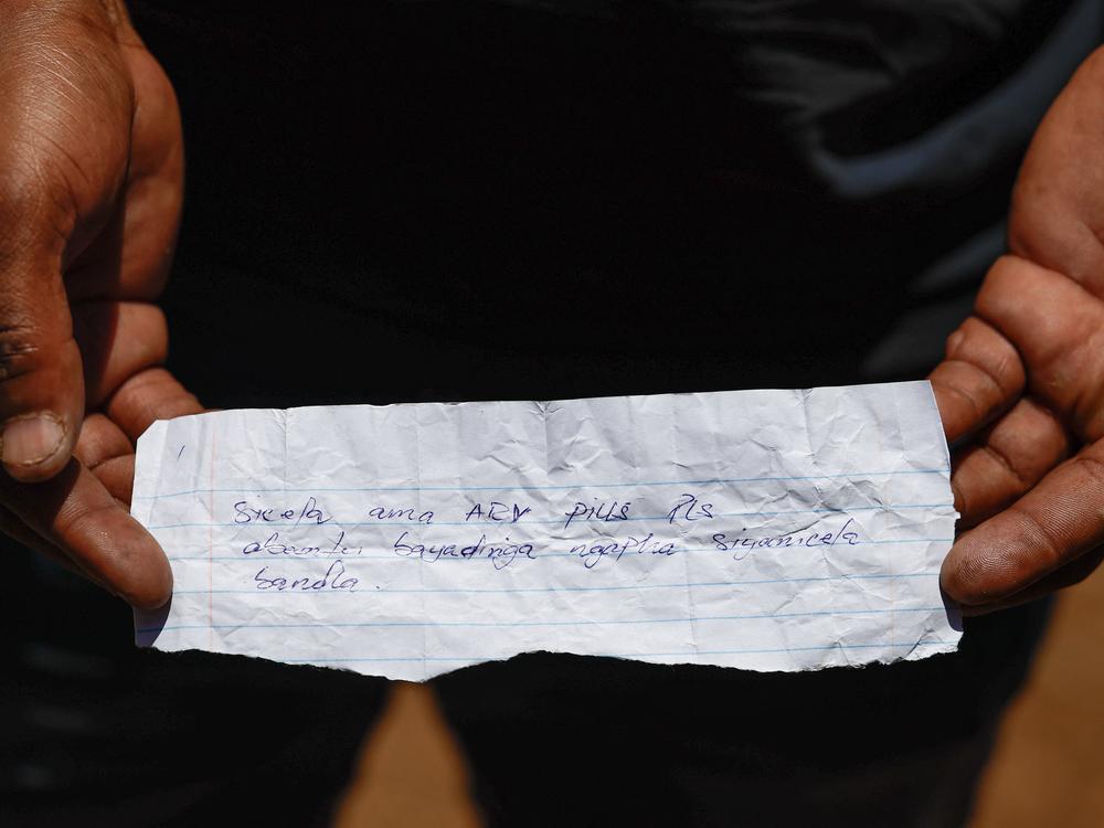 A rescue volunteer holds a note retrieved from artisanal miners operating underground written is isiXhosa language, reading, 