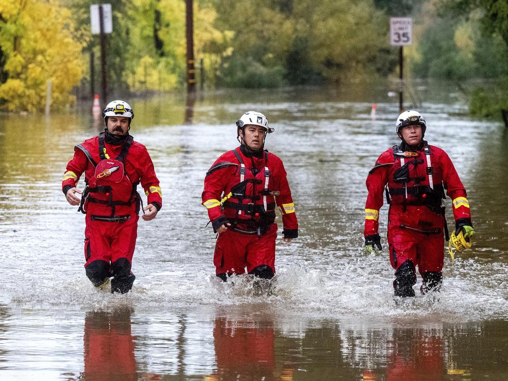 Firefighters walk through floodwaters while responding to a rescue call in unincorporated Sonoma County, Calif., on Friday, Nov. 22, 2024.
