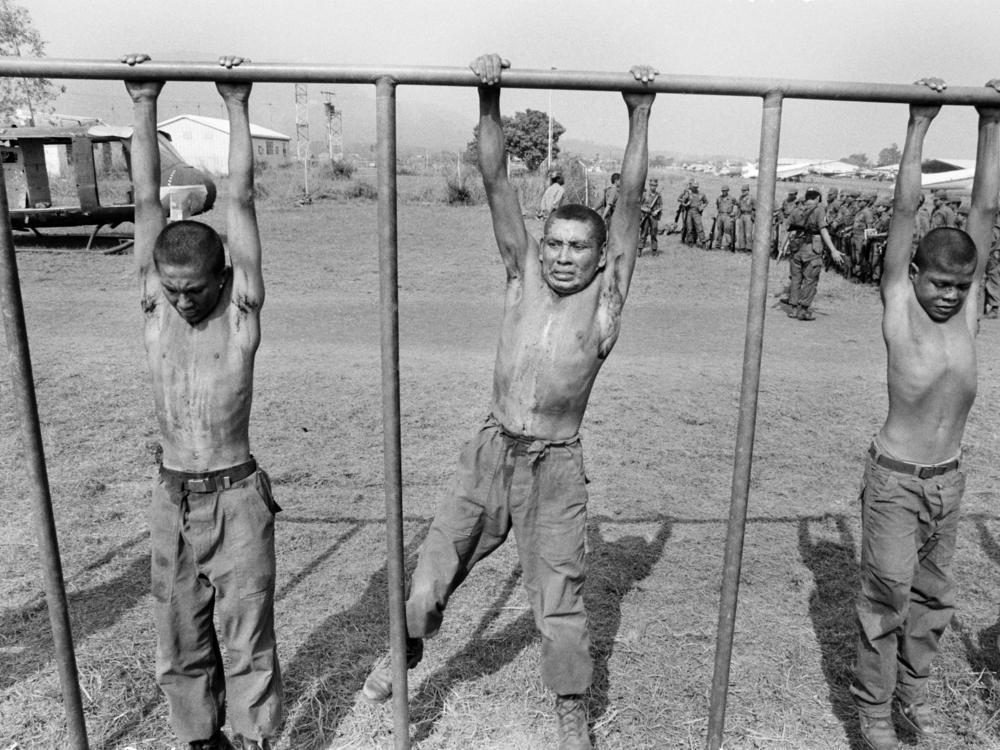 Salvadoran army recruits hang from a crossbar during a training exercise overseen by U.S. Army Rangers and Special Forces at the Ilopango air base in San Salvador, El Salvador, in March 1983.