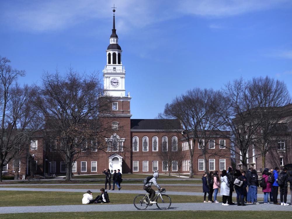 A bicyclist passes a college tour group outside the Baker Library at Dartmouth College, April 7, 2023, in Hanover, N.H.