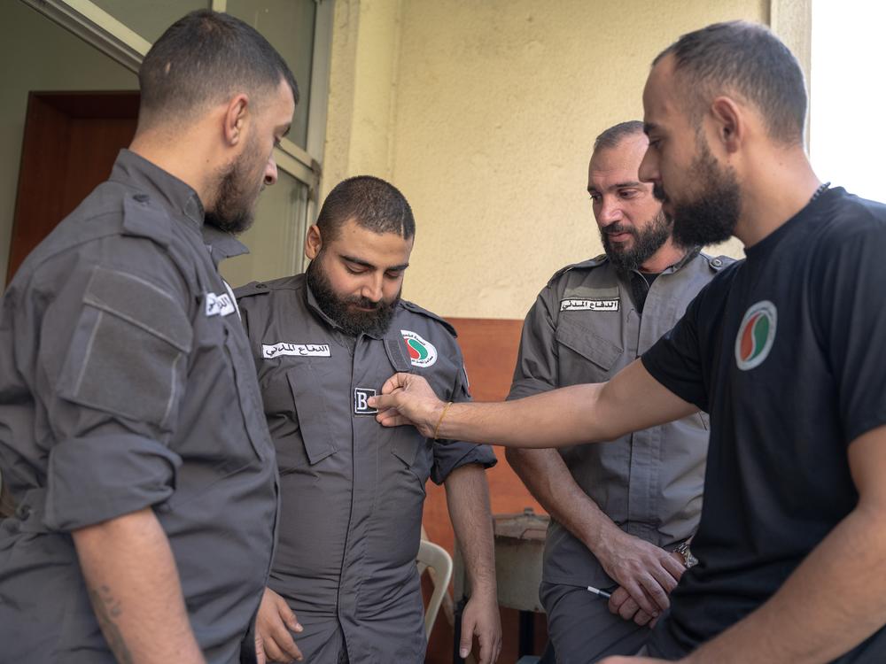 Jad Deeb, center, and other first responder volunteers talk on the balcony of their office in Beirut. One of his colleagues affixes a patch to Deeb's shirt, indicating his blood type.