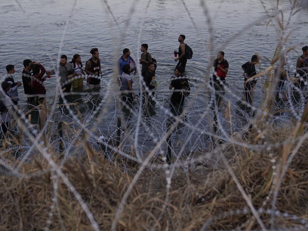 Migrants wait to climb over concertina wire after they crossed the Rio Grande and entered the U.S. from Mexico, Sept. 23, 2023, in Eagle Pass, Texas.
