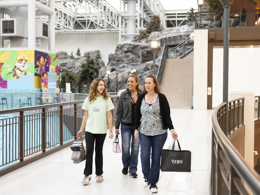 Shoppers stroll inside Mall of America on a catwalk-like bridge connecting stores, food spots and the amusement park.