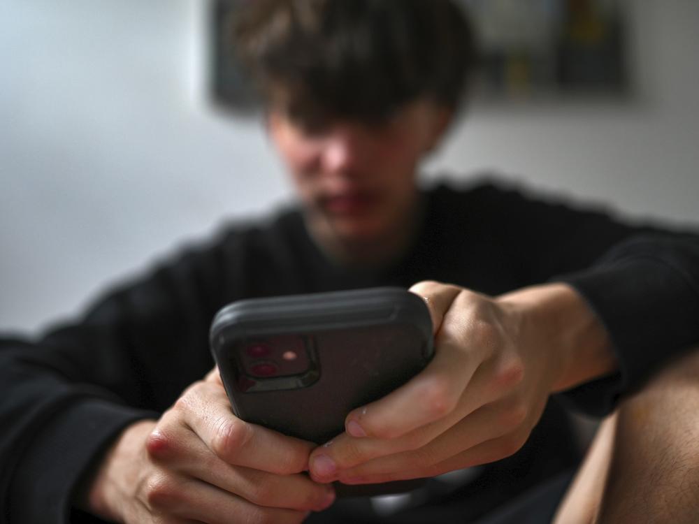 A teenager uses his mobile phone to access social media in Sydney on Nov. 13.