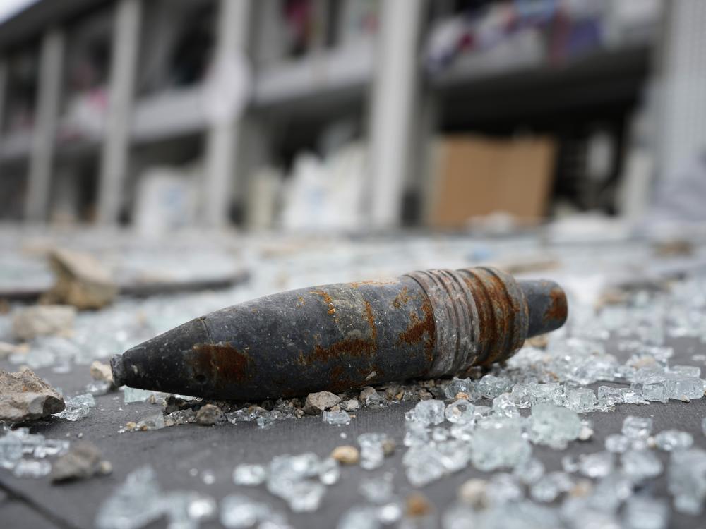 A part of an unexploded bomb lies on the street in front of a destroyed shopping center, following a ceasefire between Israel and Hezbollah that went into effect on Wednesday, in Tyre in southern Lebanon.