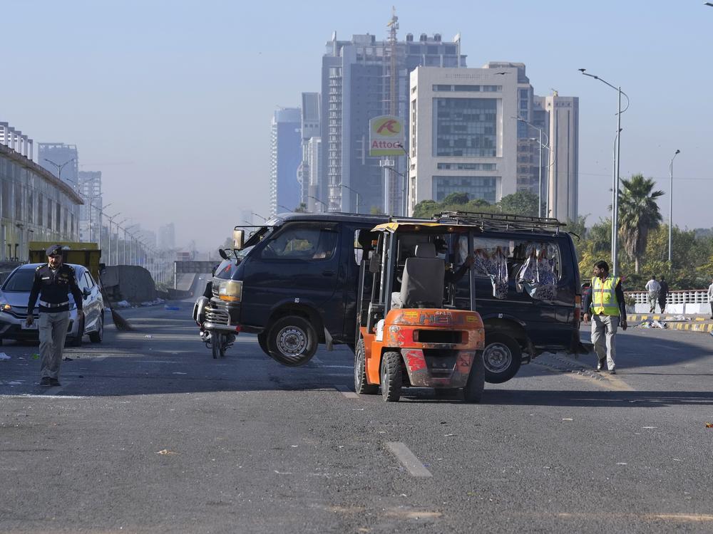 Traffic police officers remove a damaged vehicle left behind by supporters of imprisoned former Prime Minister Imran Khan's Pakistan Tehreek-e-Insaf party, when security forces launched an operation Tuesday night to disperse them, in Islamabad, Pakistan on Wednesday.