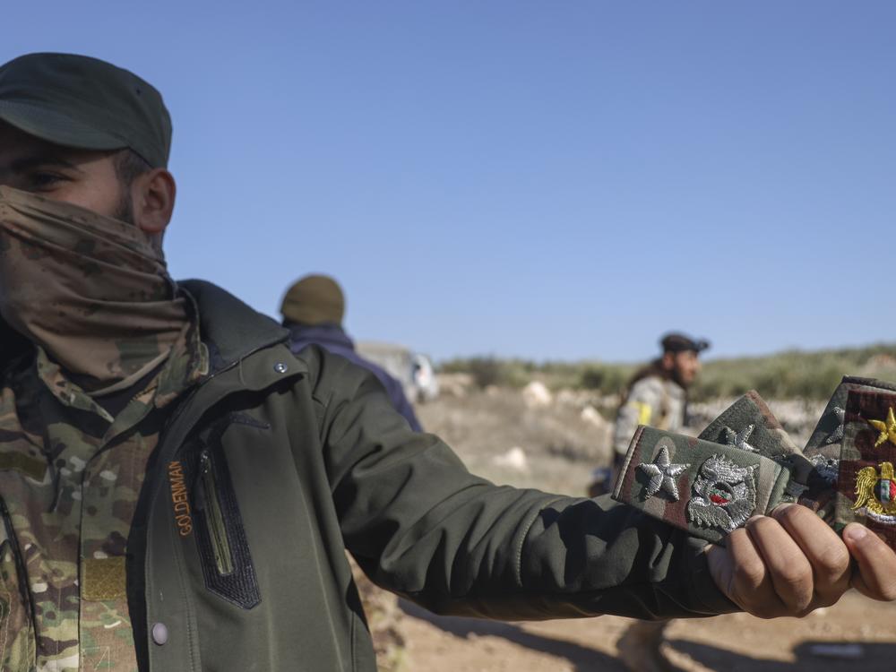 A Syrian opposition fighter displays badges allegedly belonging to Syrian army officers uniforms in Anjara, western outskirts of Aleppo, Syria, on Thursday.