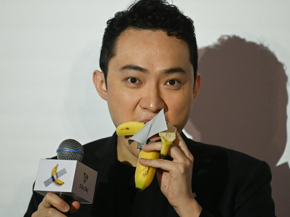 Chinese-born crypto founder Justin Sun eats a banana artwork composed of a fresh banana stuck to a wall with duct tape in Hong Kong on Friday after buying the provocative work of conceptual art by Italian artist Maurizio Cattelan at a New York auction for $6.2 million.